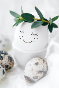 An egg with a smiling face and a wreath on its head