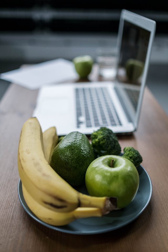 homework success:computer with fruit beside it representing a healthy study snack