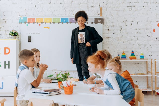 teacher and young students in classroom; referring to inequality symbols in math